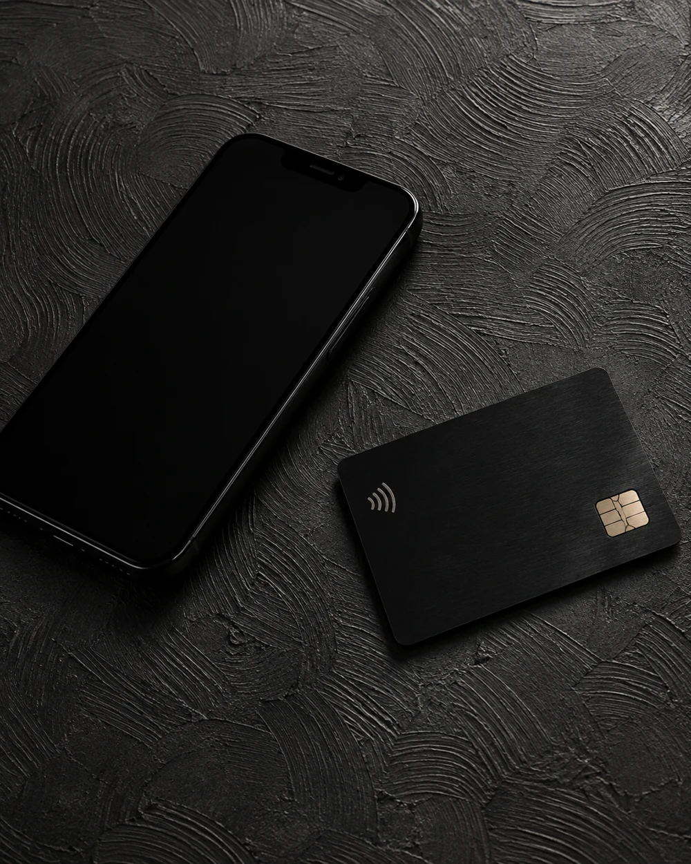 Smartphone and unbranded payment card on a charcoal desk